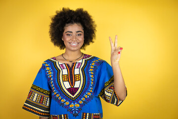 African american woman wearing african clothing over yellow background showing and pointing up with fingers number two while smiling confident and happy