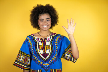 African american woman wearing african clothing over yellow background showing and pointing up with fingers number five while smiling confident and happy