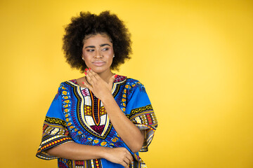 African american woman wearing african clothing over yellow background touching painful neck, sore throat for flu, clod and infection