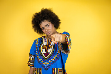 African american woman wearing african clothing over yellow background pointing with finger to the camera and to you, confident gesture looking serious
