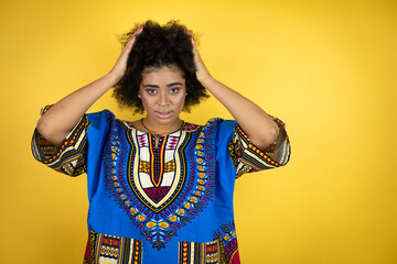African american woman wearing african clothing over yellow background thinking looking tired and bored with hands on head
