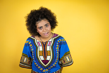 African american woman wearing african clothing over yellow background afraid and shocked with surprise and amazed expression, fear and excited face.