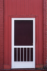 White screen door on a painted red wall
