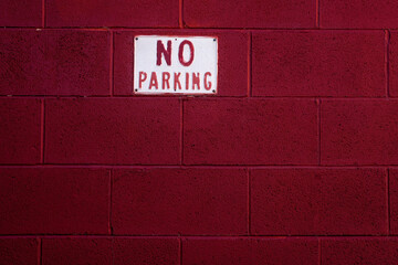 No parking sign on painted brick wall

