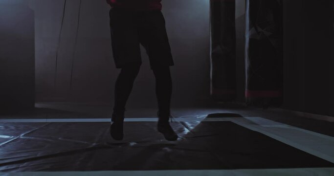 Close-up, athlete jumping rope, dark gym with smoke. Athlete training, jumping rope, bottom view of the camera. 4k, ProRes