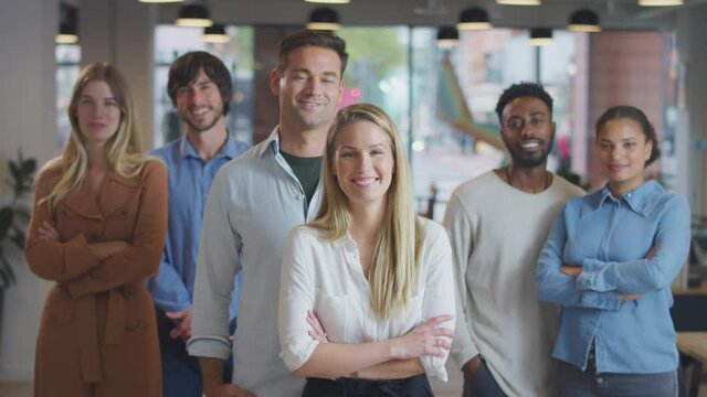 Portrait of multi-cultural business team standing in modern open plan office - shot in slow motion