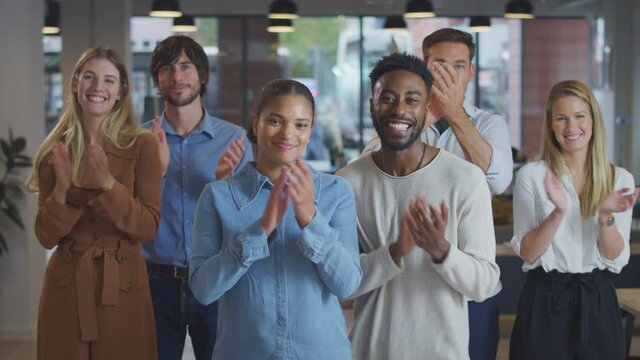Portrait of multi-cultural business team standing in modern open plan office and clapping - shot in slow motion
