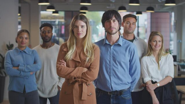 Portrait of couple leading multi-cultural business team standing in modern open plan office and clapping - shot in slow motion