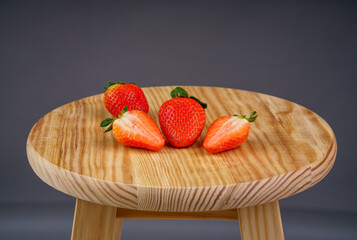 Ripe strawberries on a wooden chair on dark background