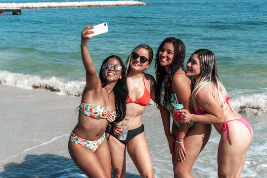 Four pretty girls enjoying a day at the beach, taking pictures of each other.