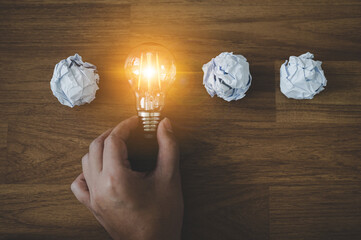 Hand choose light bulb and crumpled office paper. Concept of inspiration creative idea thinking and future technology innovation