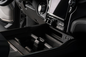 cup holder close up inside a black luxury car, touch screen system display