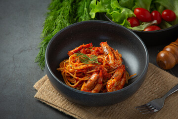 spaghetti with shrimps in tomato sauce on dark background