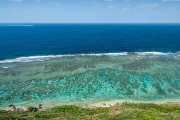 Beautiful scenery seen from above, incredible colors of blue and green ocean, amazing coral reefs and a motorboat appearing on the background. Miyako Island.