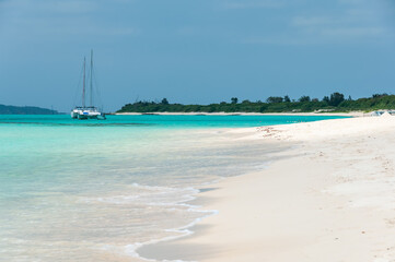 White sand beach, emerald green sea and a catamaran docked in its beautiful transparent waters. Miyako Island.