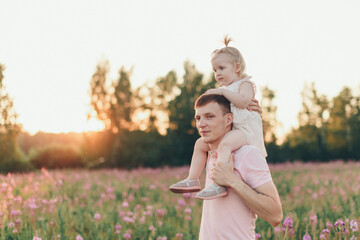 a happy father with daughter walks through a flower meadow. Love and spring blooming. Man and little girl. Father's day