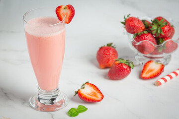 Strawberry smoothie in glass on marble background
