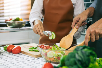 Asian couple preparing healthy salad in the kitchen.