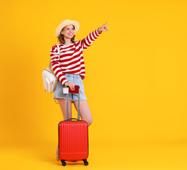 Cheerful travelling woman with suitcase pointing away