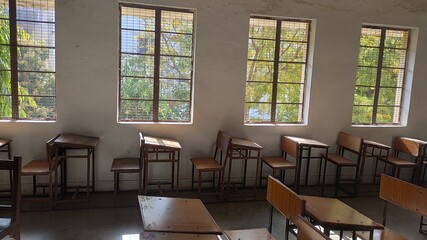 Wooden chairs and stool in a classroom arranged one behind another well organised