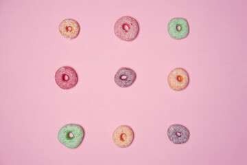 Multicolored donuts lined up neatly isolated on a pink background. Delicious snacks suitable to be eaten in spare time. Practical mini donuts to carry wherever you are. Sweet and savory donuts.