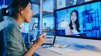 Asia businesswoman using desktop talk to colleagues about plan in video call meeting at living...