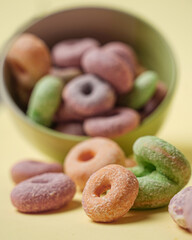 Pile of donuts of different colors popped out or fell out of the bowl. Good snacks suitable to be eaten in spare time. Practical mini donuts to carry wherever you are. Sweet and savory donuts.