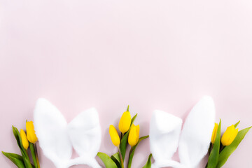 Easter concept. White fluffy rabbit ears, yellow tulips on a pink background