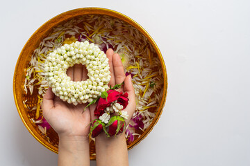 Thai traditional jasmine garland and Colorful flower in water bowls decorating and perfume, marly limestone, plastic water gun on table