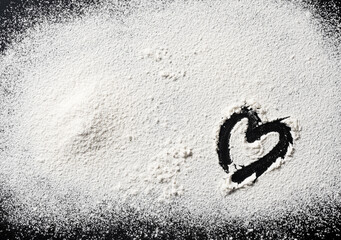 Flour in the shape of a heart on a black background