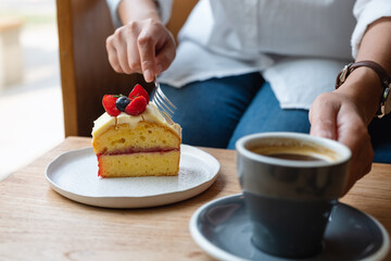 Closeup image of a woman eating cake and drinking coffee in cafe