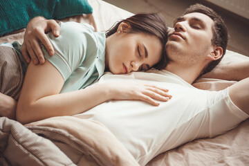 Adorable couple lying in bed and napping together embracing in a morning