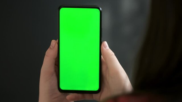 Back View of Woman at Phone with Green Screen for Copy Space. Chromakey Mock Up Without Tracking Markers. 20s Lady Watching Video News on Couch Close up.