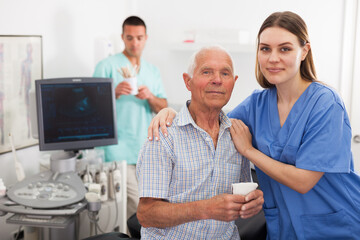 Obraz premium Woman doctor and elderly man patient before ultrasound diagnostic, man on background