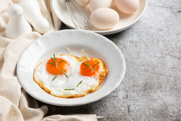 Fried eggs in a white plate on dark background