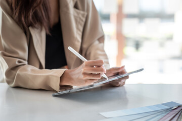 Close up of woman designer working using a tablet at the desk at the office.