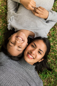 Vertical photography of young latin mother and her daughter lying on the grass.