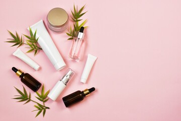 Natural organic eco cosmetics. Beauty SPA branding mock-up. Cosmetic containers with cream and lotion, cotton flowers on pink background. flat lay, top view. Copy space.