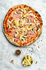 Pizza with artichokes, champignons, ham and mozzarella on a light background, top view. Traditional Italian pizza