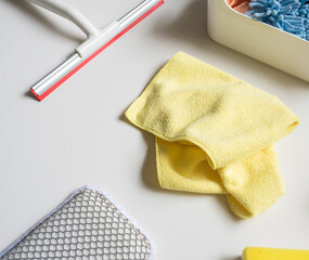 High angle closeup of yellow microfibre cleaning cloth and other equipment on white background (selective focus)