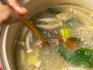 Dipping beef slices in a Thai Hotpot soup. Selective focus.