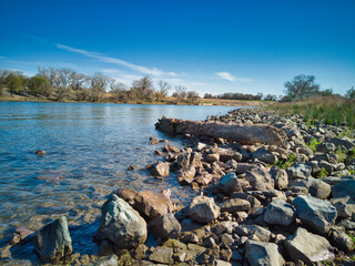 Log resting on rocks on the shore of the American river 