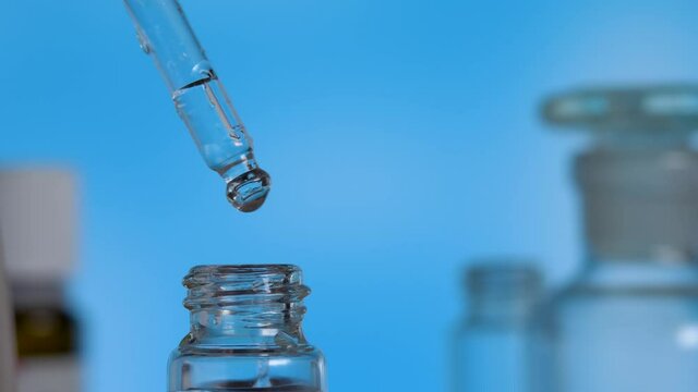 Droplet dosing biological and ecological plant herbal on blue background. Alternative healthy medicine and healthcare concept. Laboratory flasks with clear liquid. Production of natural cosmetics