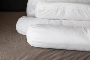 Closeup Group of comfort bedding, white Bolster or long pillows with no case cover on cotton brown bed sheet