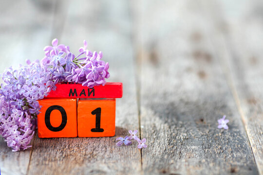 Wooden calendar with Russian text May 1 and a bouquet of lilacs on a wooden background.Spring day, empty space for text. International Workers' Day