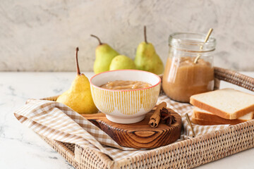 Tray with tasty pear jam and bread on light background