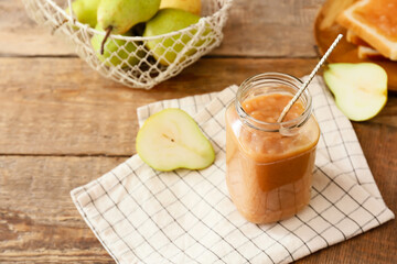 Jar of tasty pear jam on wooden table