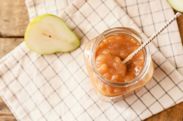 Jar of tasty pear jam on table