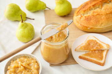 Jar of tasty pear jam with bread on table