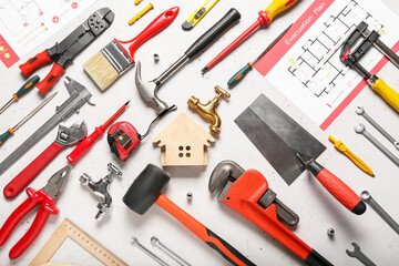 Composition with figure of house and construction tools on light background